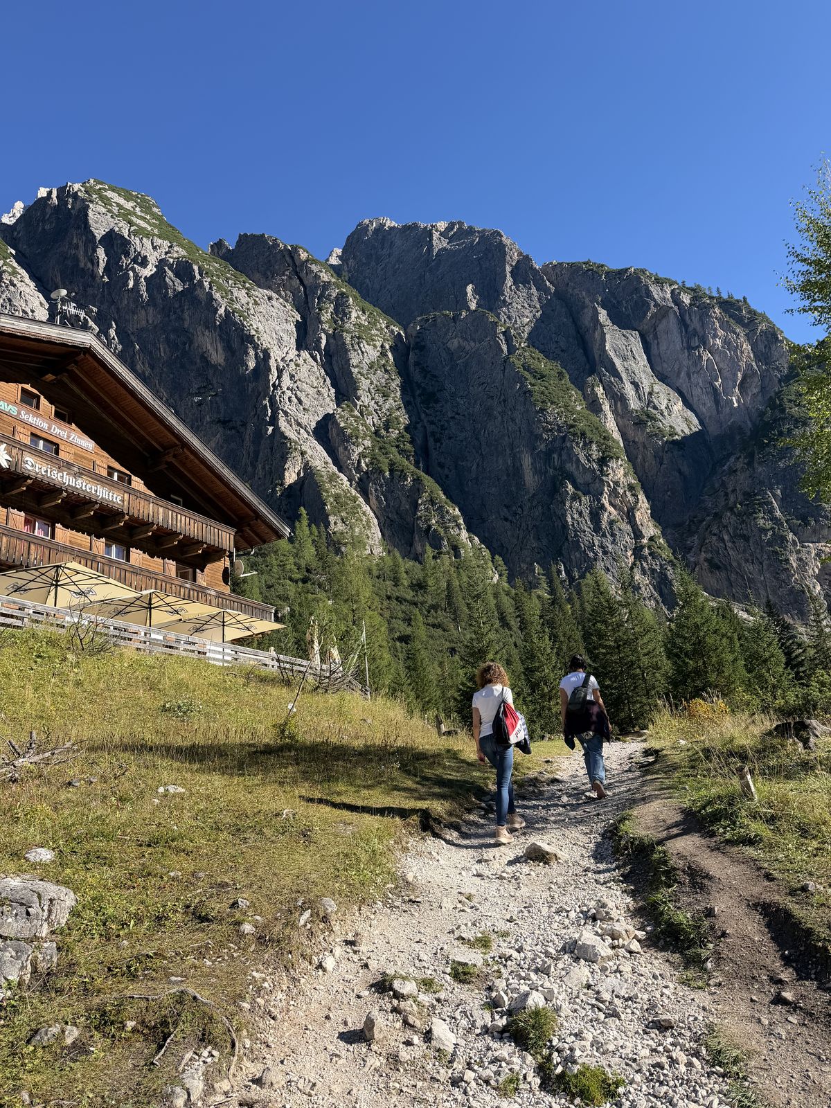 Zwei Frauen wandern auf dem Weg zur Dreischusterhütte vor einer Felswand